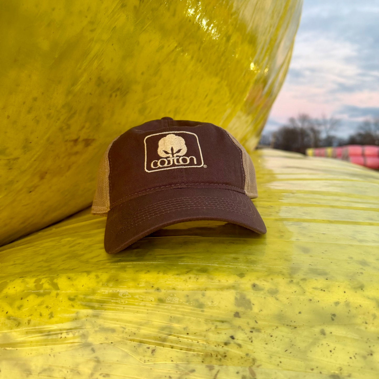 Brown and tan mesh back hat with adjustable fit and embroidered Seal of Cotton logo