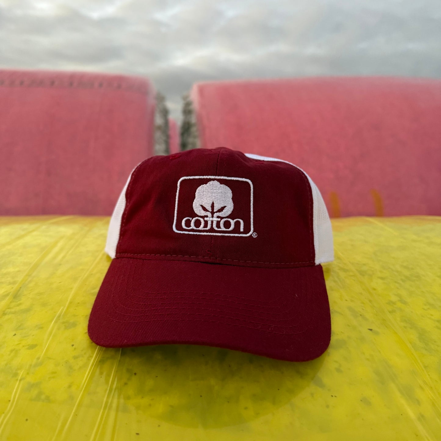 Maroon and white mesh back hat with adjustable fit and embroidered Seal of Cotton logo